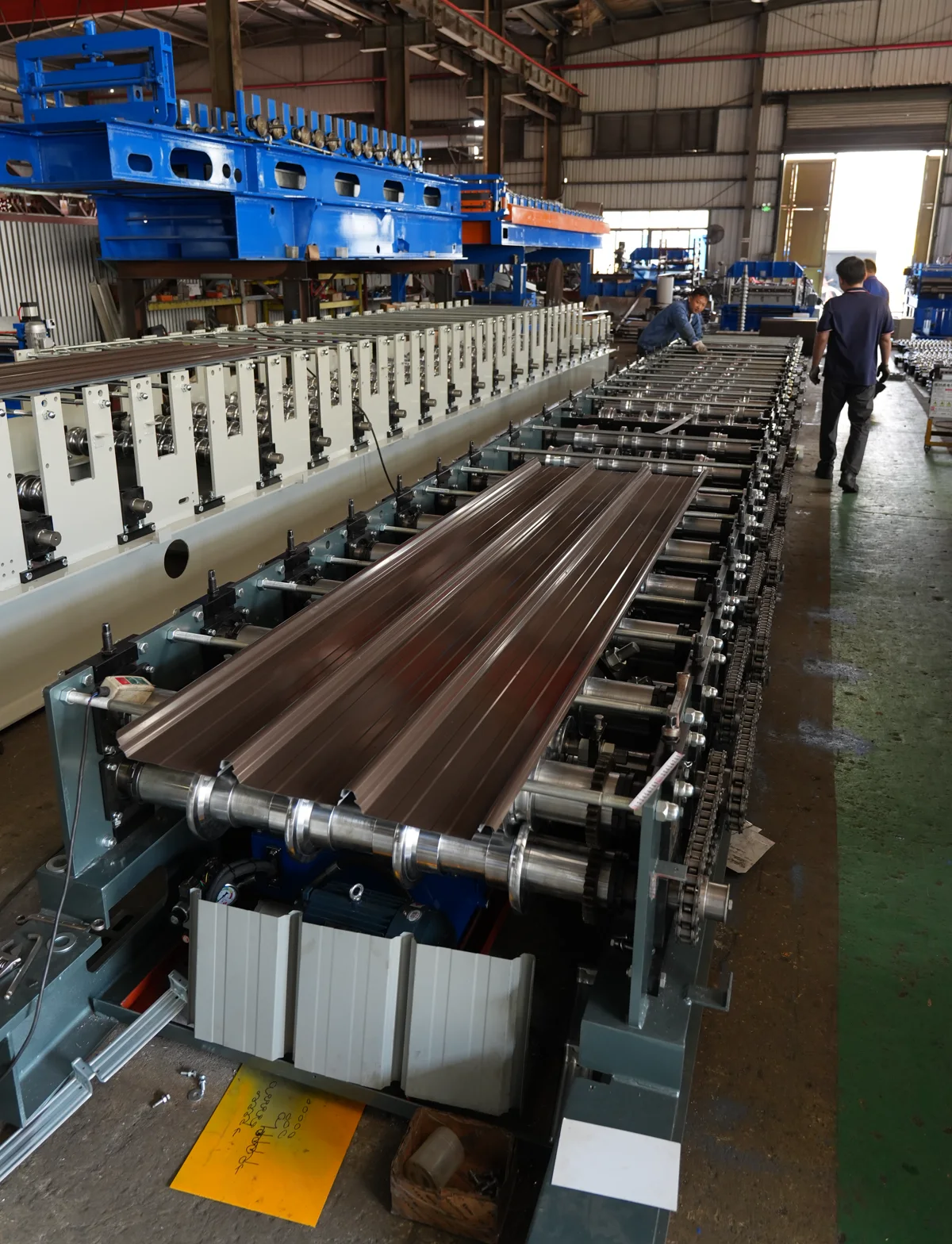 Brown profiled roof sheet on the run-out of a roll forming line during a workshop visit
